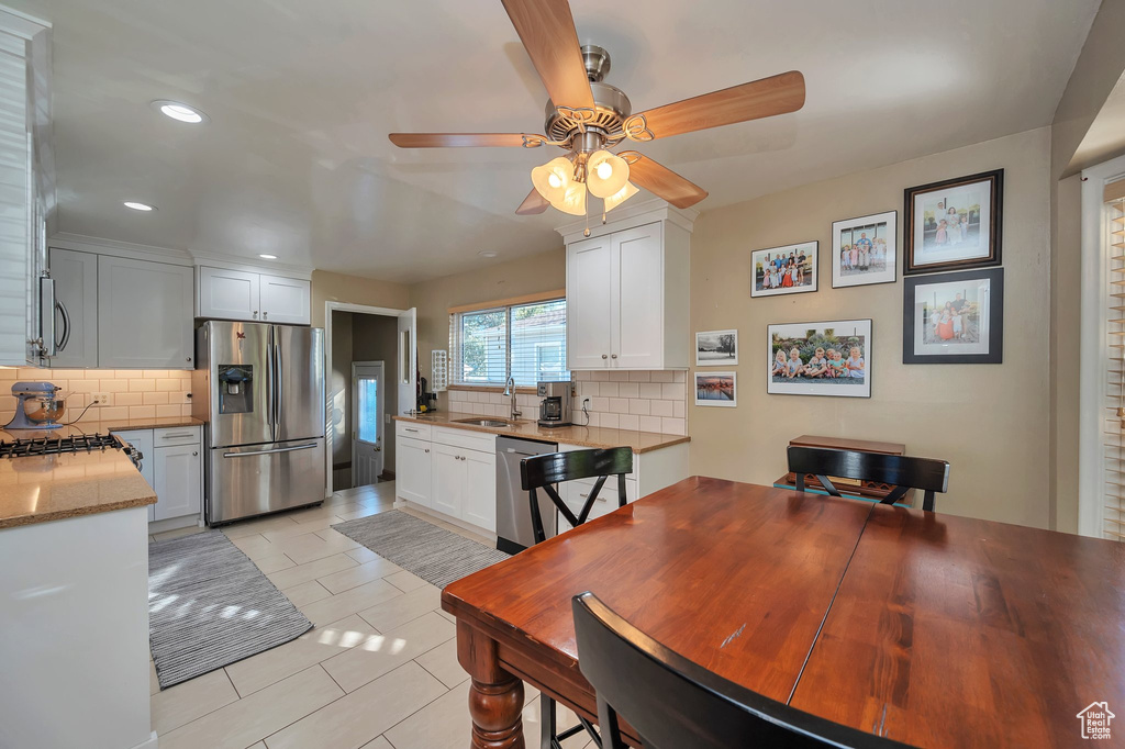 Kitchen with tasteful backsplash, sink, stainless steel appliances, and white cabinets