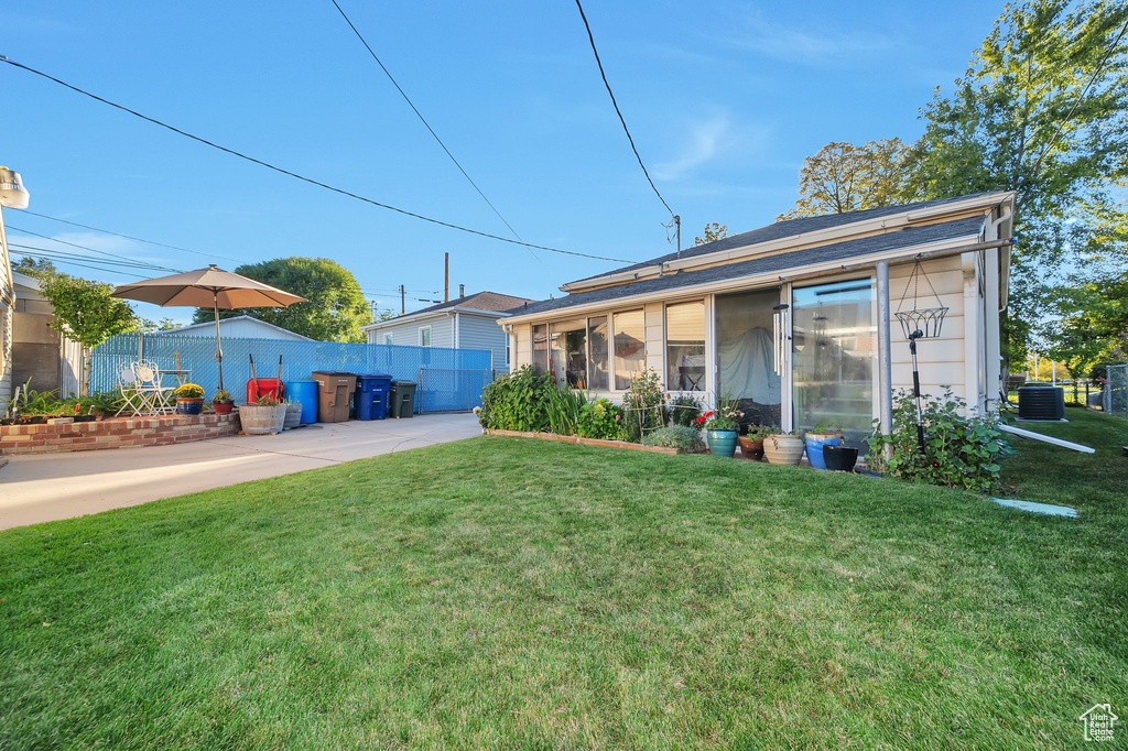 Rear view of property with central AC, a sunroom, and a lawn