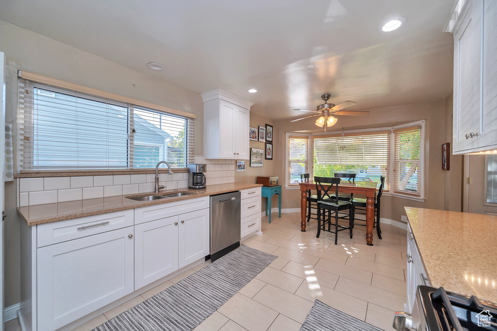 Kitchen with white cabinets, light tile patterned flooring, sink, tasteful backsplash, and appliances with stainless steel finishes