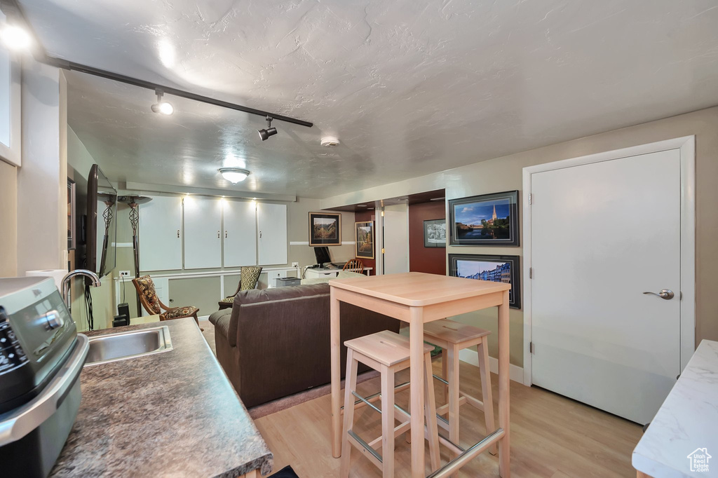 Kitchen with track lighting, a textured ceiling, sink, and light hardwood / wood-style flooring