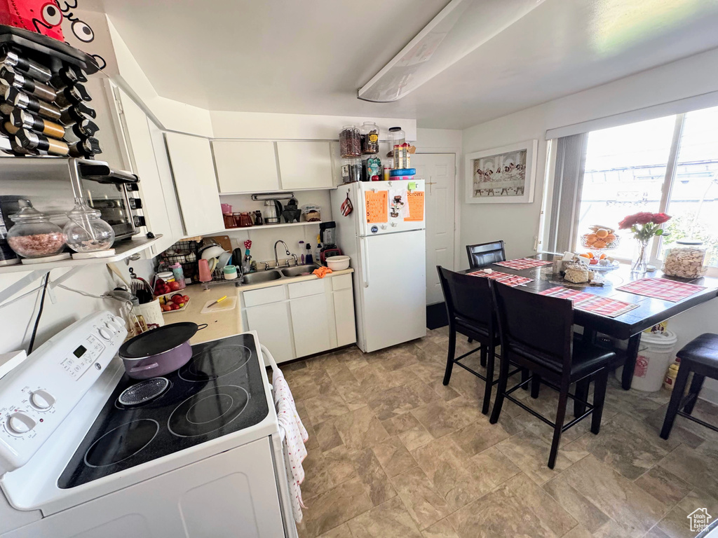 Kitchen featuring sink, white appliances, and white cabinetry