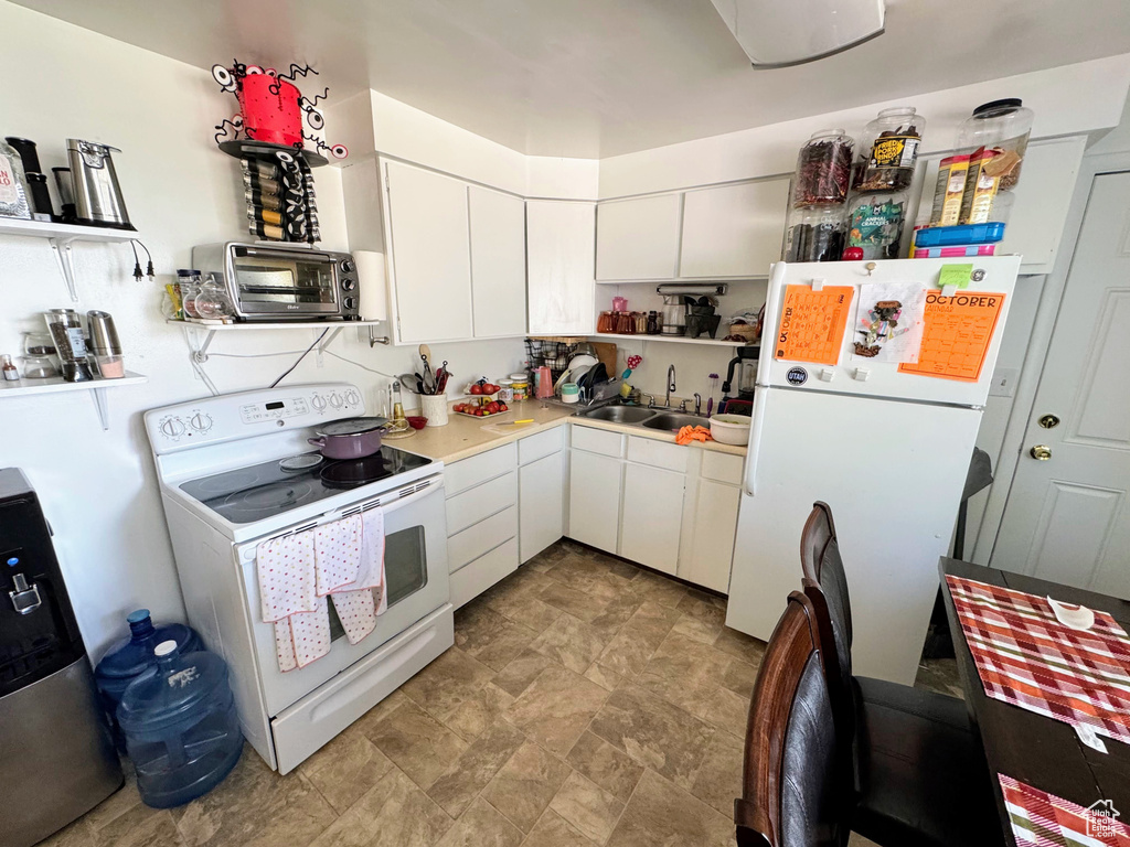 Kitchen with sink, white appliances, and white cabinetry