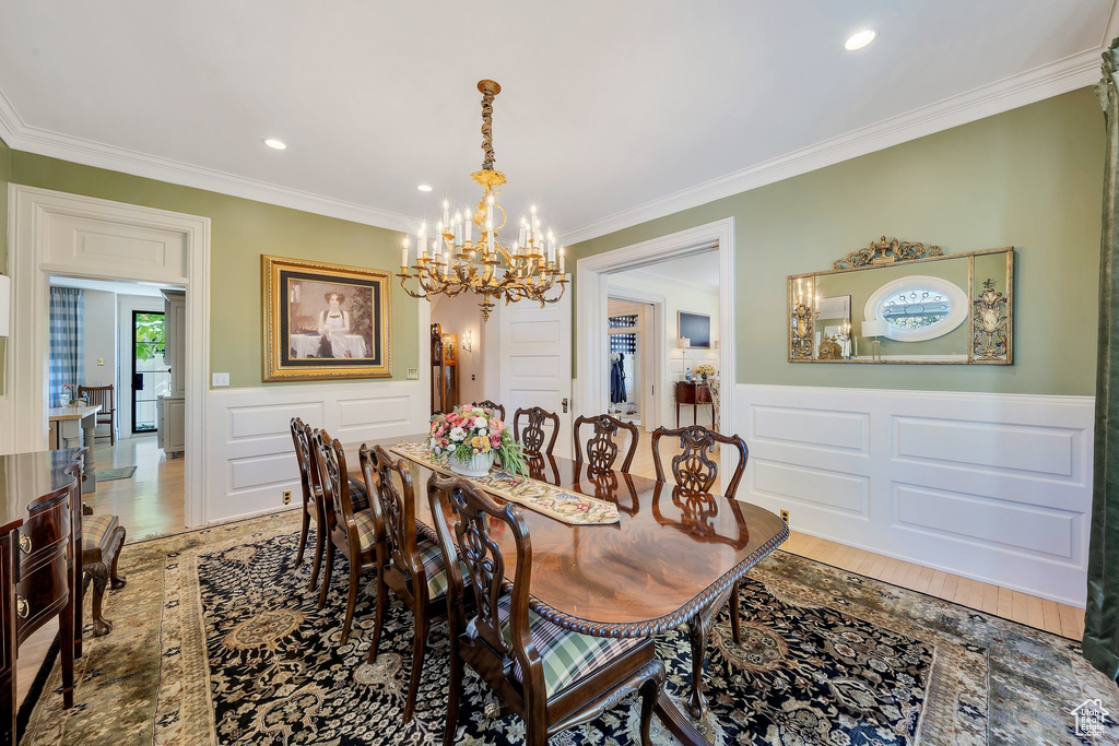 Dining room featuring light hardwood / wood-style floors, crown molding, and a chandelier