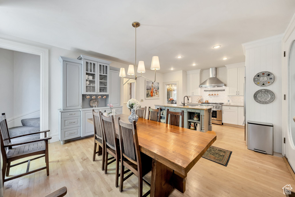 Dining room featuring sink, light wood-type flooring, and an inviting chandelier