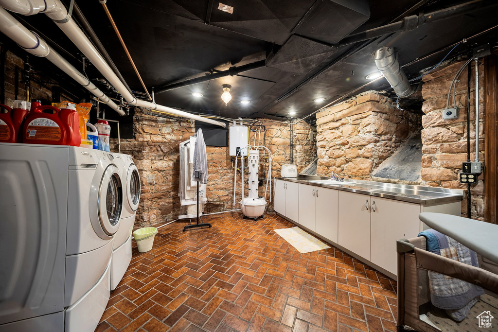 Washroom featuring gas water heater, separate washer and dryer, and cabinets