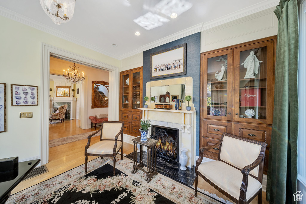 Living area featuring ornamental molding, a notable chandelier, hardwood / wood-style floors, and a fireplace