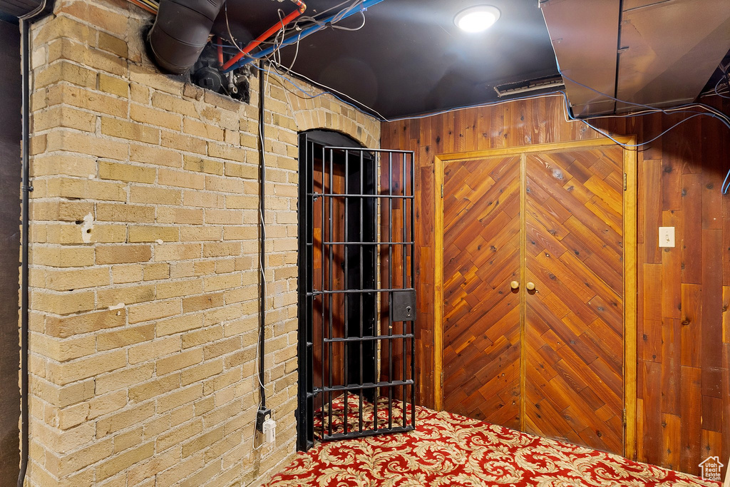 Basement with wooden walls, brick wall, and carpet