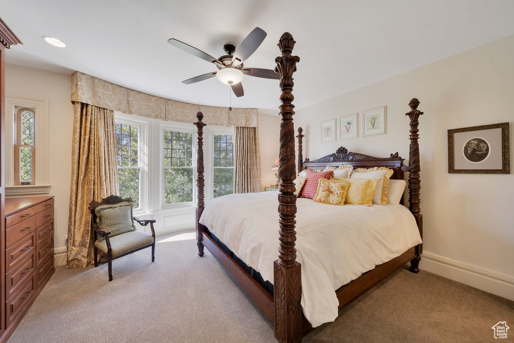 Carpeted bedroom featuring ceiling fan and multiple windows