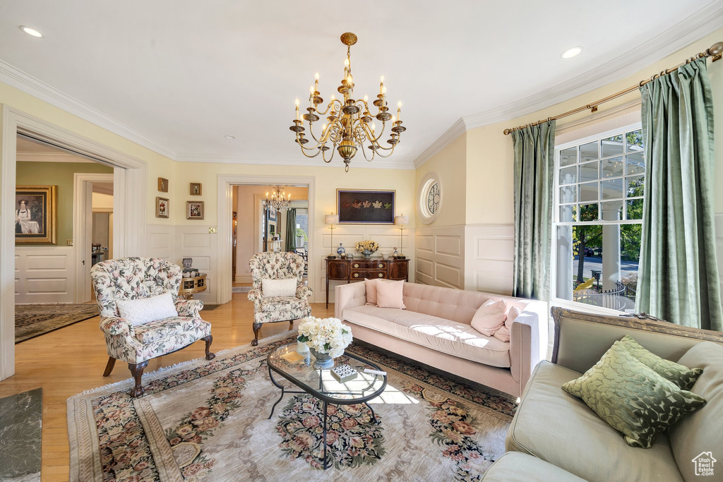 Living room featuring an inviting chandelier, ornamental molding, and light hardwood / wood-style floors