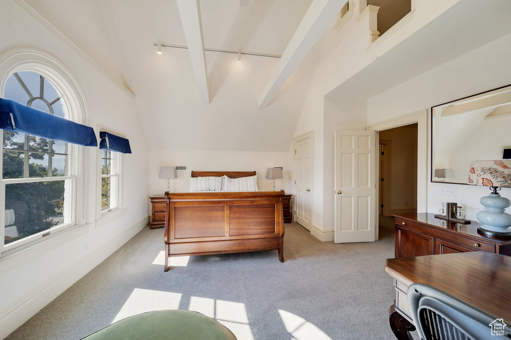 Carpeted bedroom with beam ceiling, track lighting, and high vaulted ceiling