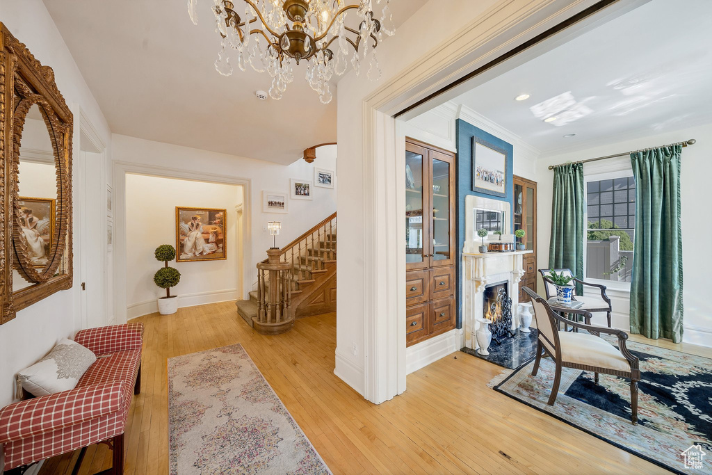 Hall with a notable chandelier, crown molding, and hardwood / wood-style flooring