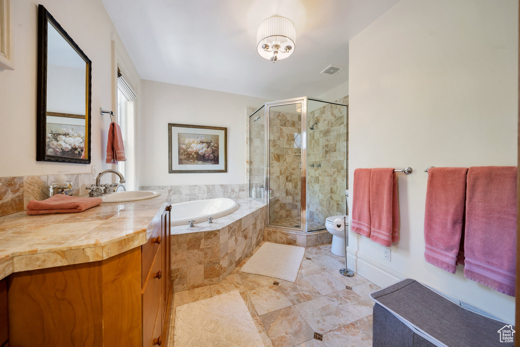 Full bathroom with toilet, vanity, and separate shower and tub