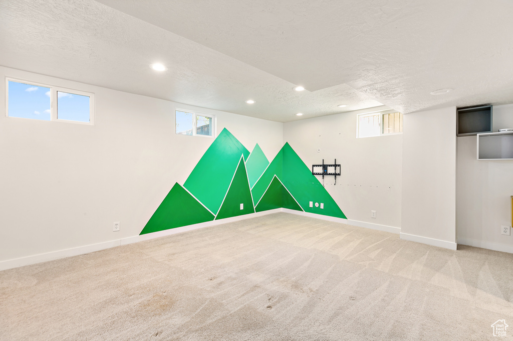 Basement with a textured ceiling and carpet flooring