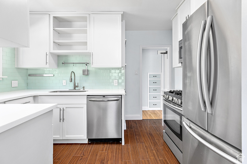 Kitchen featuring tasteful backsplash, sink, stainless steel appliances, dark hardwood / wood-style floors, and white cabinetry