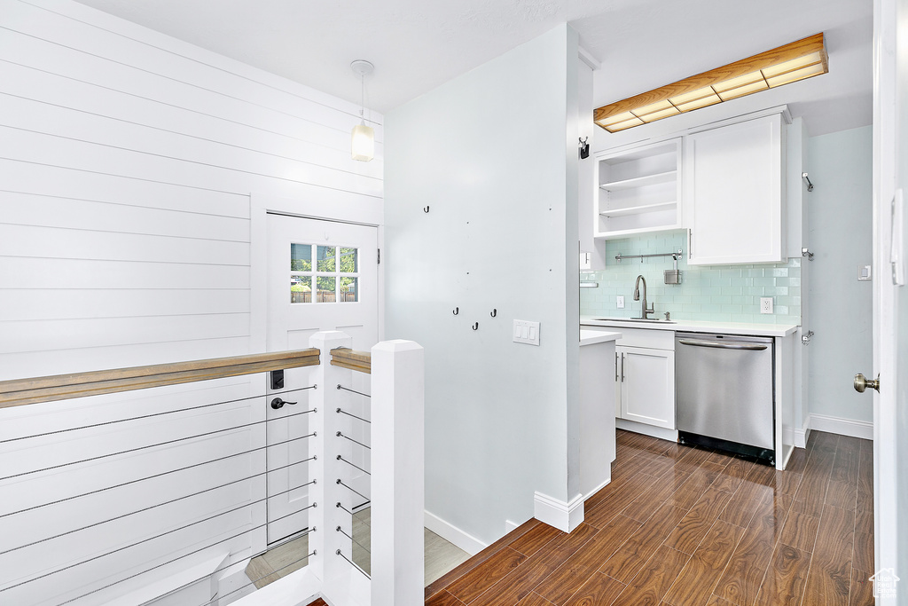 Kitchen featuring decorative backsplash, dark wood-type flooring, decorative light fixtures, dishwasher, and white cabinetry