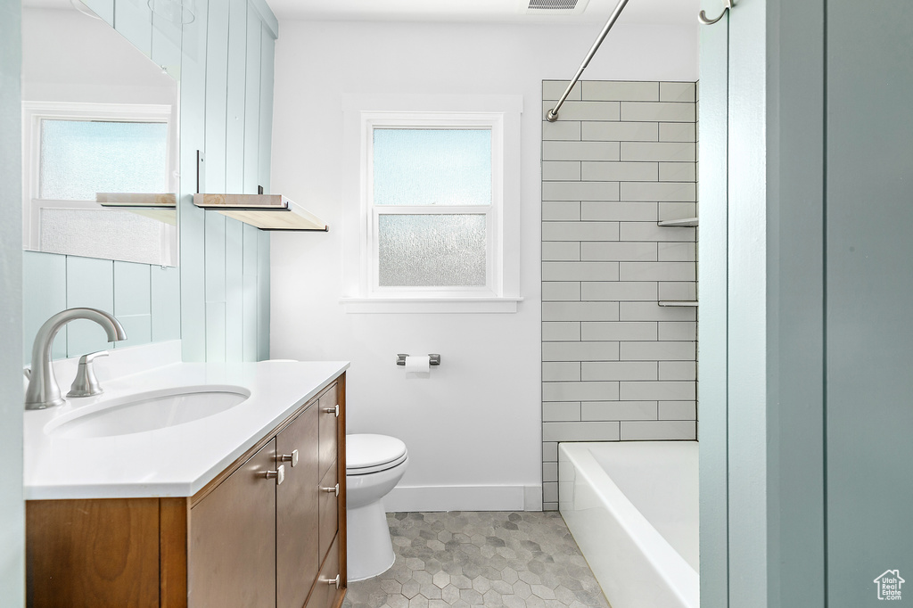 Full bathroom featuring tiled shower / bath, vanity, tile patterned flooring, and toilet