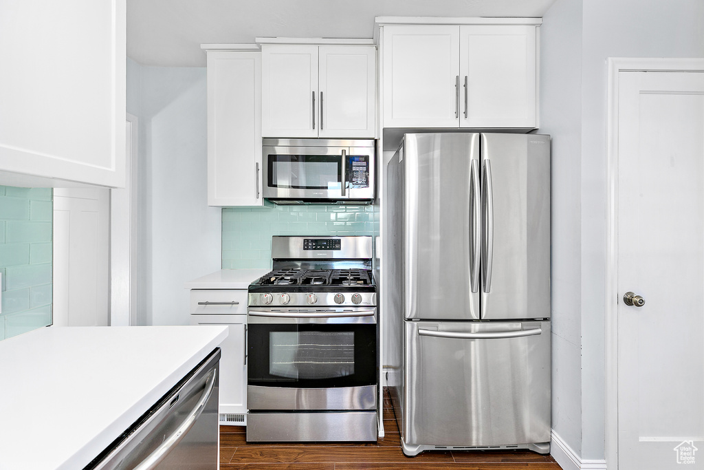 Kitchen featuring appliances with stainless steel finishes, white cabinetry, and backsplash