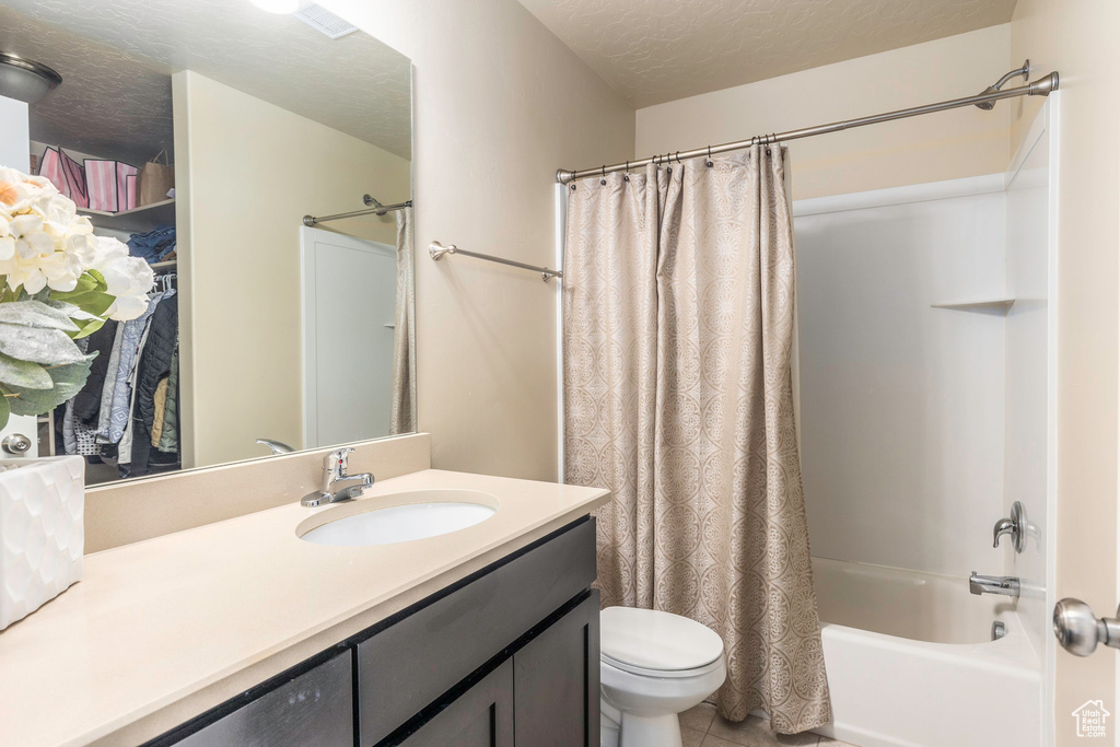 Full bathroom featuring tile patterned flooring, toilet, shower / bath combo, vanity, and a textured ceiling
