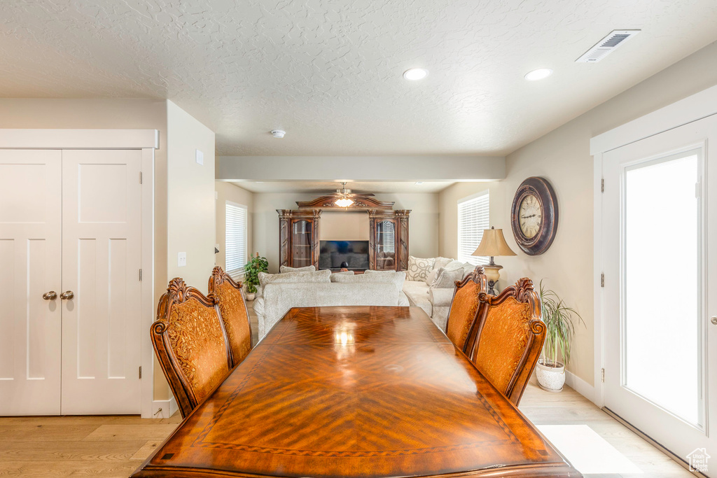 Dining room with ceiling fan, a textured ceiling, and light wood-type flooring