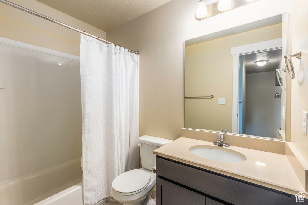 Full bathroom with shower / bath combination with curtain, vanity, toilet, and a textured ceiling
