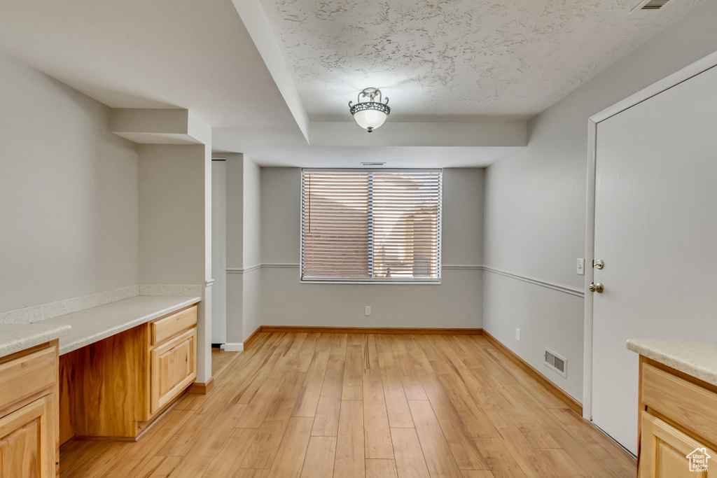 Unfurnished dining area with light wood-type flooring and a textured ceiling