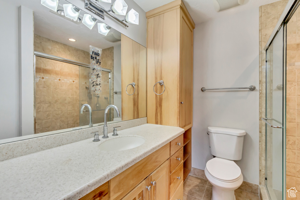 Bathroom with tile patterned floors, vanity, a shower with door, and toilet