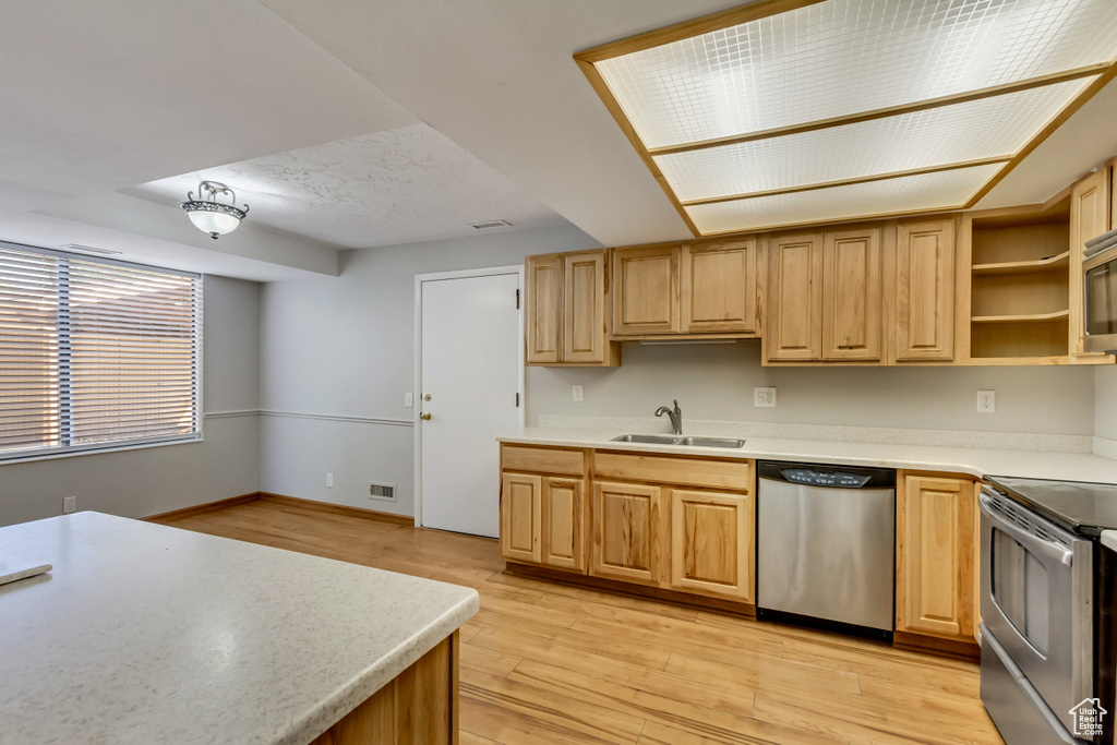 Kitchen featuring light brown cabinetry, appliances with stainless steel finishes, light wood-type flooring, and sink