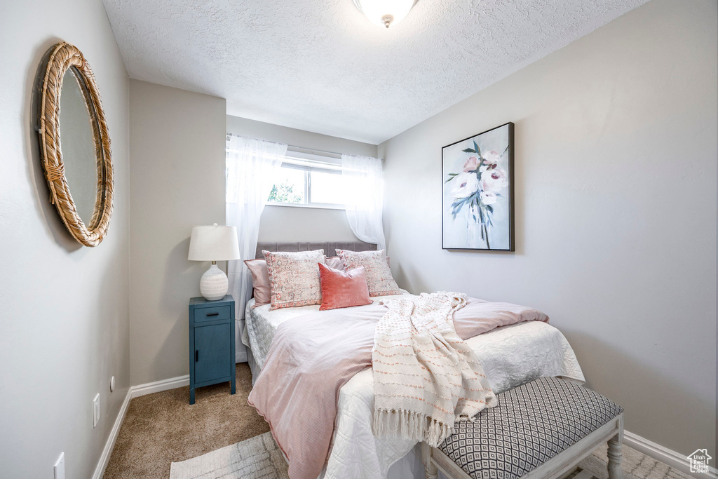 Bedroom featuring light colored carpet and a textured ceiling