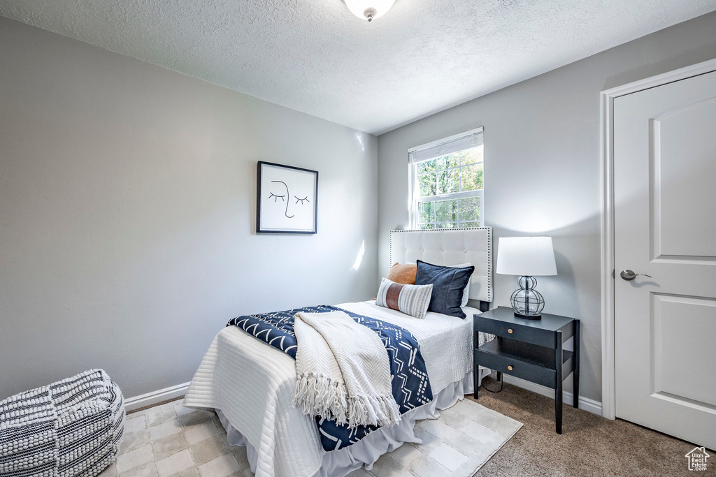 Bedroom with light carpet and a textured ceiling