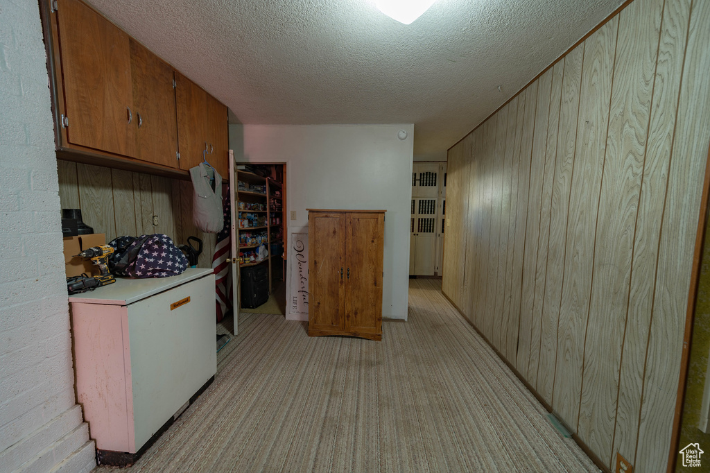 Kitchen featuring fridge, a textured ceiling, and wood walls