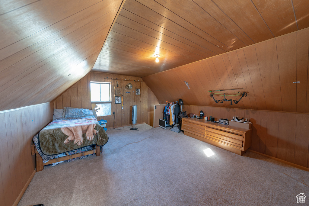 Bedroom featuring lofted ceiling, wood walls, wooden ceiling, and carpet flooring