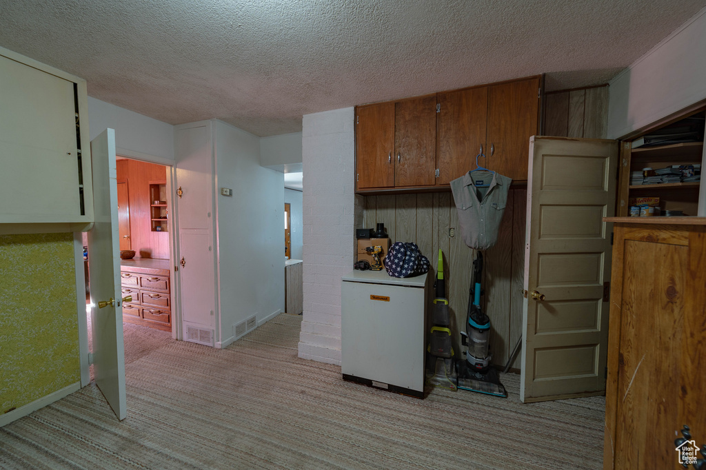 Kitchen featuring light colored carpet and a textured ceiling