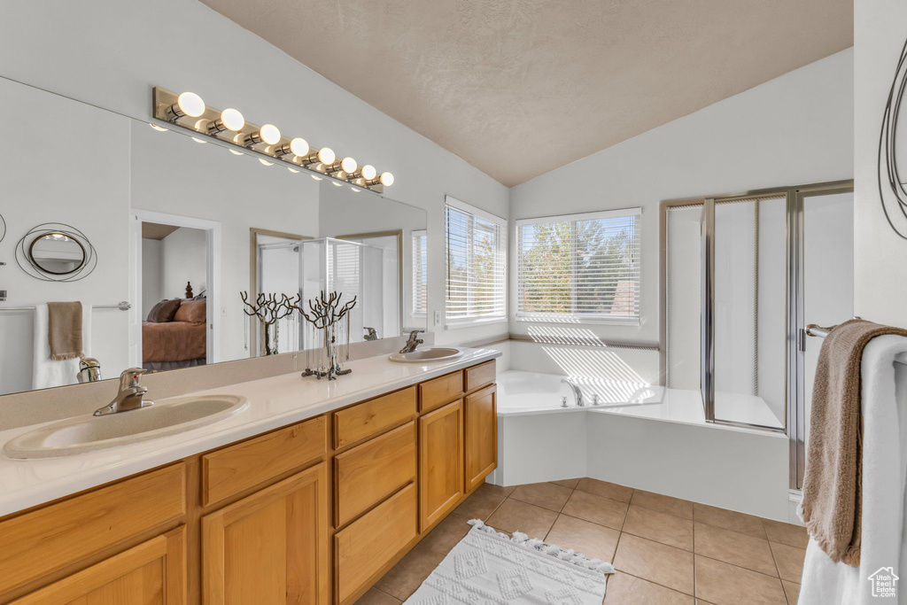 Bathroom with separate shower and tub, tile patterned floors, vanity, and vaulted ceiling