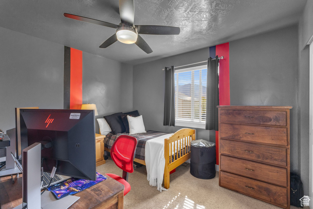 Carpeted bedroom with a textured ceiling and ceiling fan