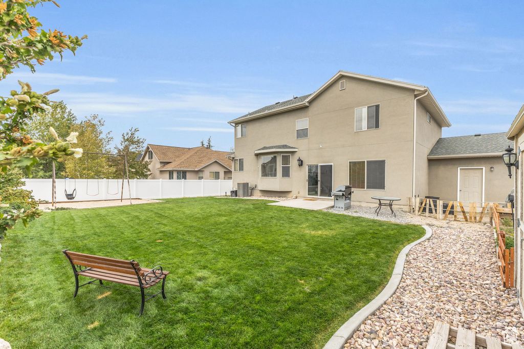 Back of property featuring a lawn, a patio area, and central AC