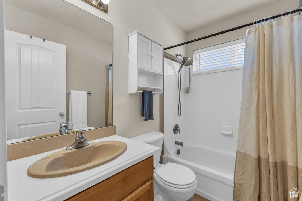 Full bathroom featuring vanity, toilet, and shower / bathtub combination with curtain