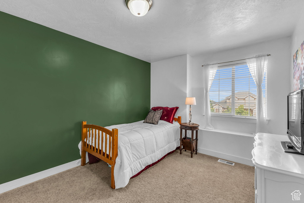 Bedroom with a textured ceiling and light carpet