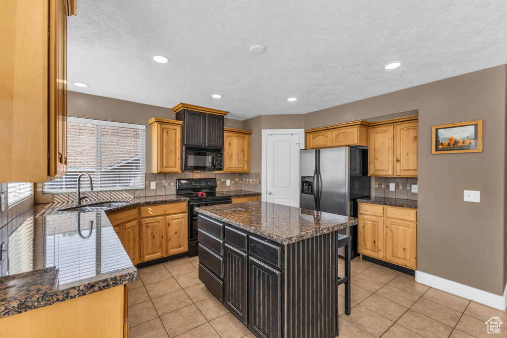 Kitchen featuring a kitchen island, sink, decorative backsplash, black appliances, and light tile patterned floors