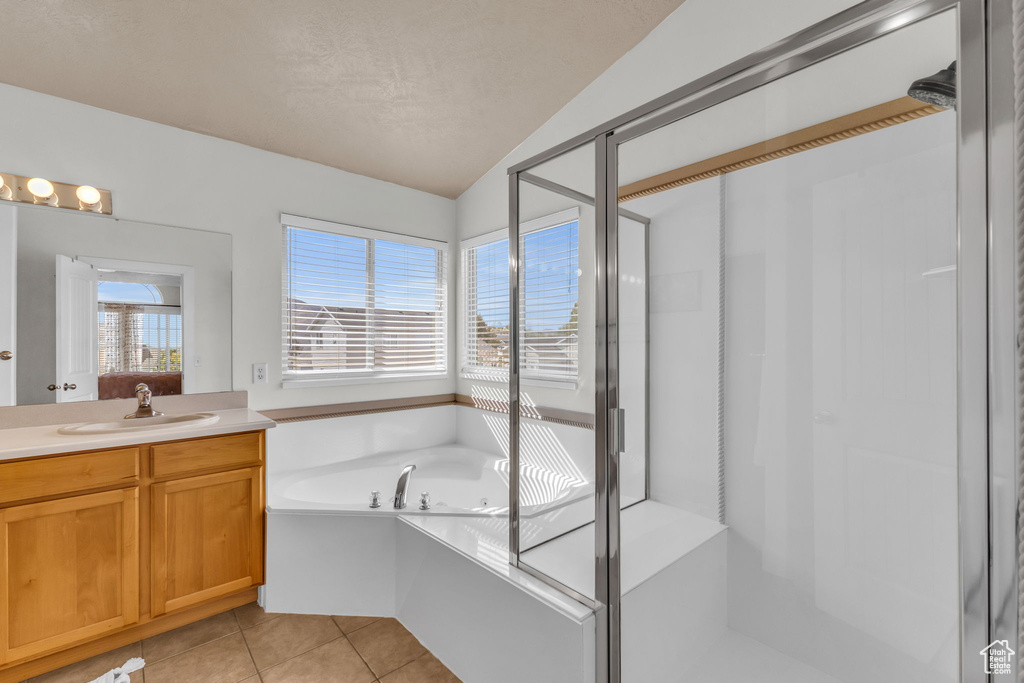 Bathroom with lofted ceiling, tile patterned floors, vanity, and plus walk in shower