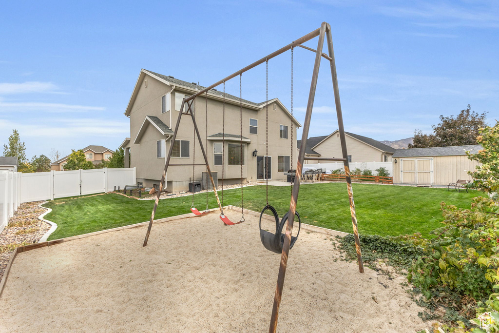 Rear view of property featuring a patio, a lawn, and a shed