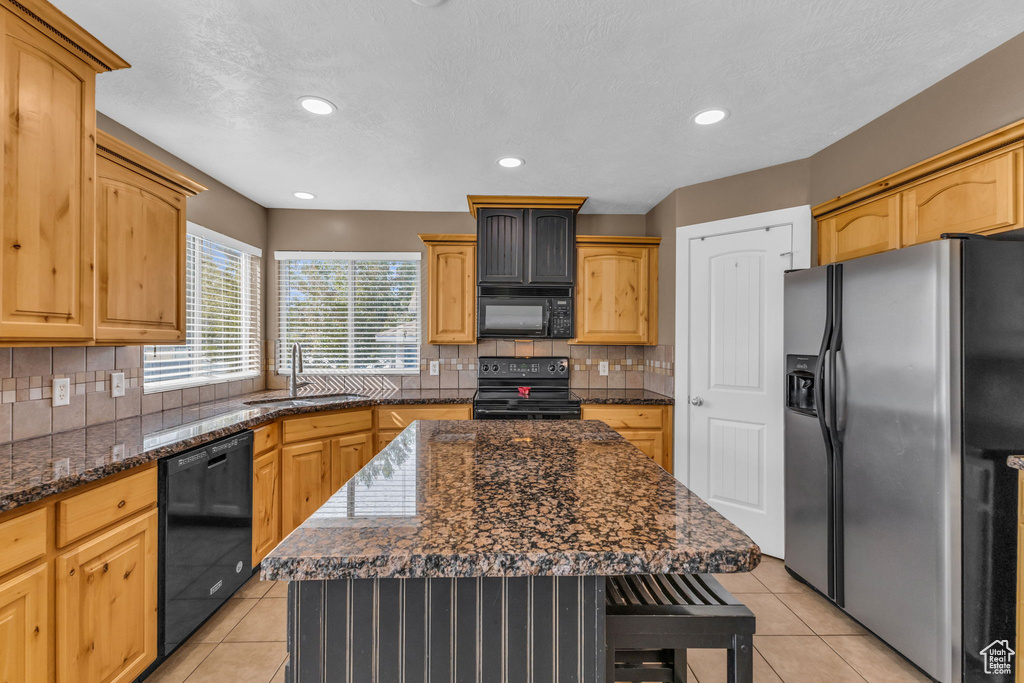 Kitchen featuring black appliances, a center island, tasteful backsplash, sink, and light tile patterned floors