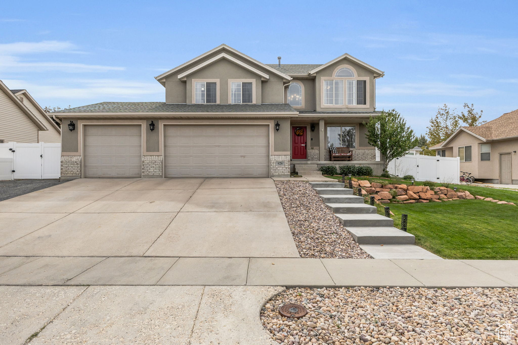 View of front facade with a porch, a front yard, and a garage