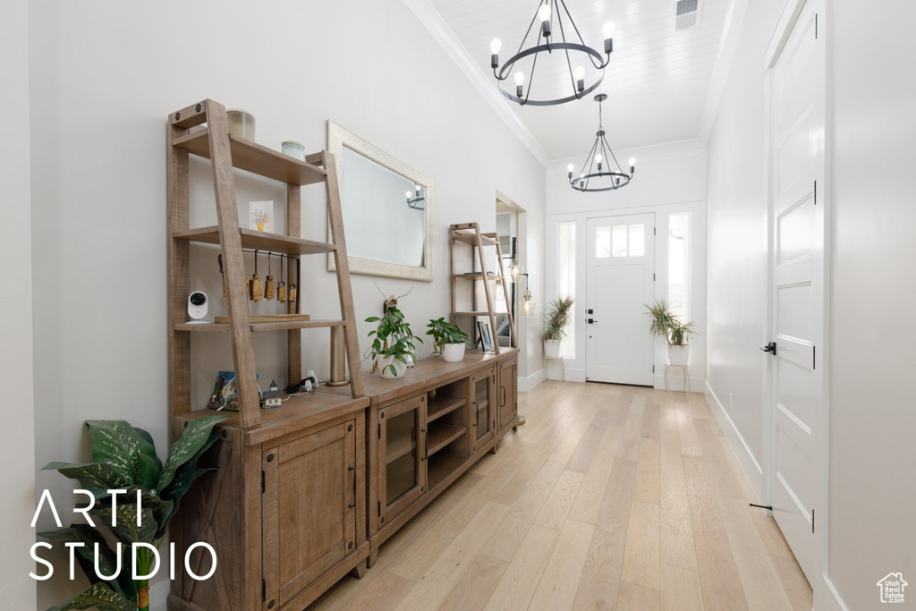 Foyer featuring an inviting chandelier, crown molding, and light hardwood / wood-style flooring