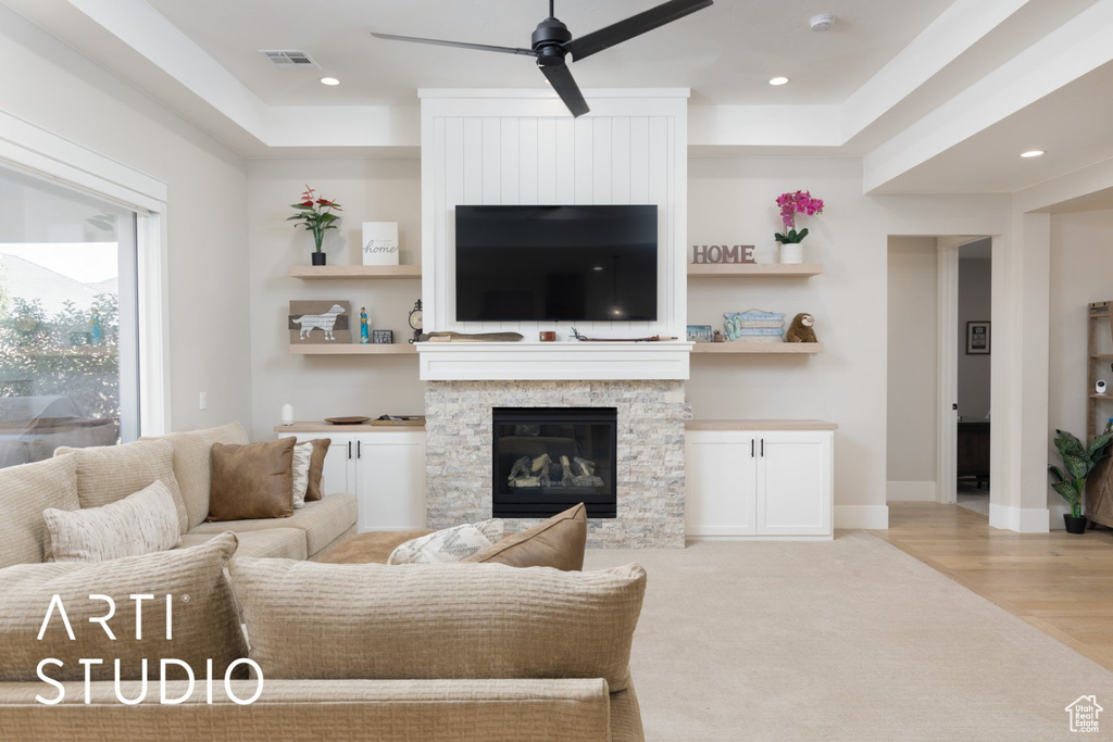 Living room featuring ceiling fan, light hardwood / wood-style flooring, and a stone fireplace