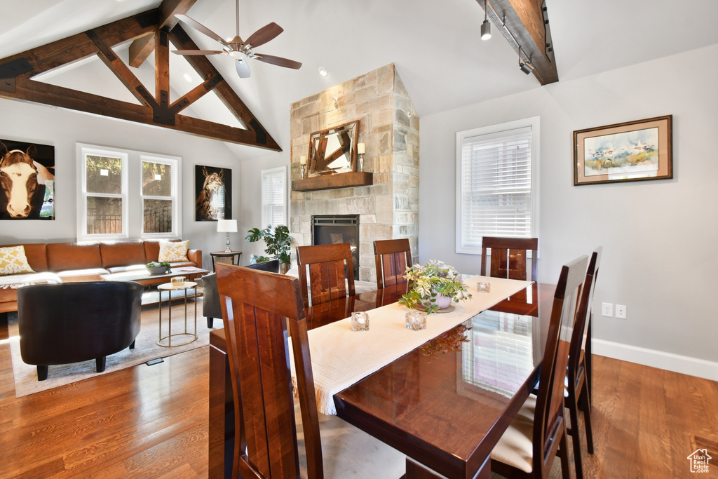 Dining room featuring a fireplace, beamed ceiling, hardwood / wood-style flooring, and a healthy amount of sunlight