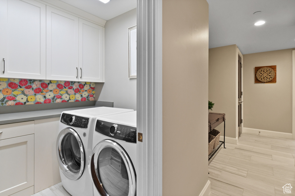 Laundry room featuring cabinets, light hardwood / wood-style flooring, and washer and dryer