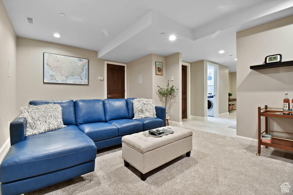 Living room with washer / clothes dryer and light colored carpet