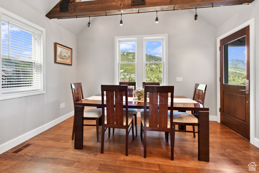 Dining space with hardwood / wood-style flooring, lofted ceiling, and a healthy amount of sunlight