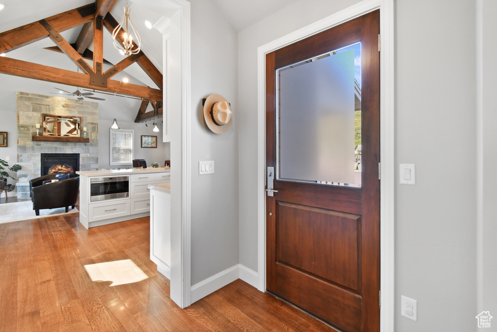 Entrance foyer featuring vaulted ceiling with beams, light wood-type flooring, plenty of natural light, and a fireplace