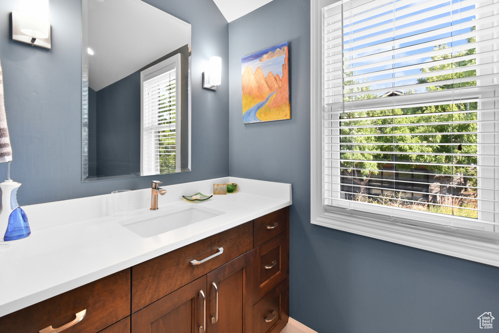 Bathroom featuring a wealth of natural light, vaulted ceiling, and vanity